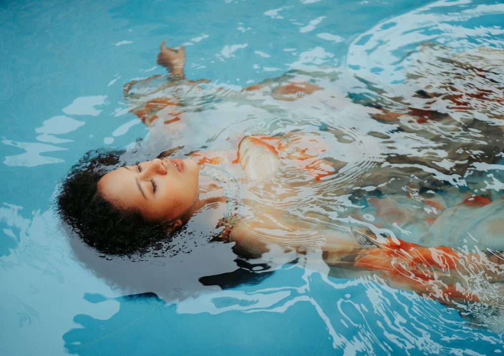 chica relajada en la piscina flotando