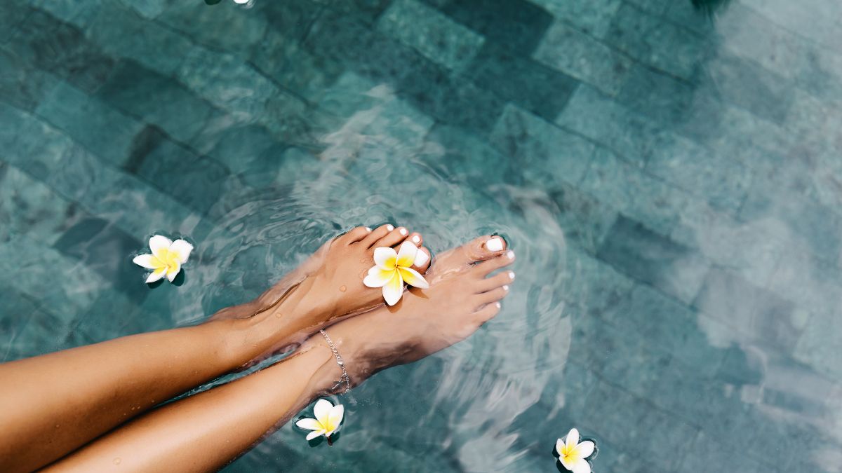pies de chica en la piscina con flores en el agua